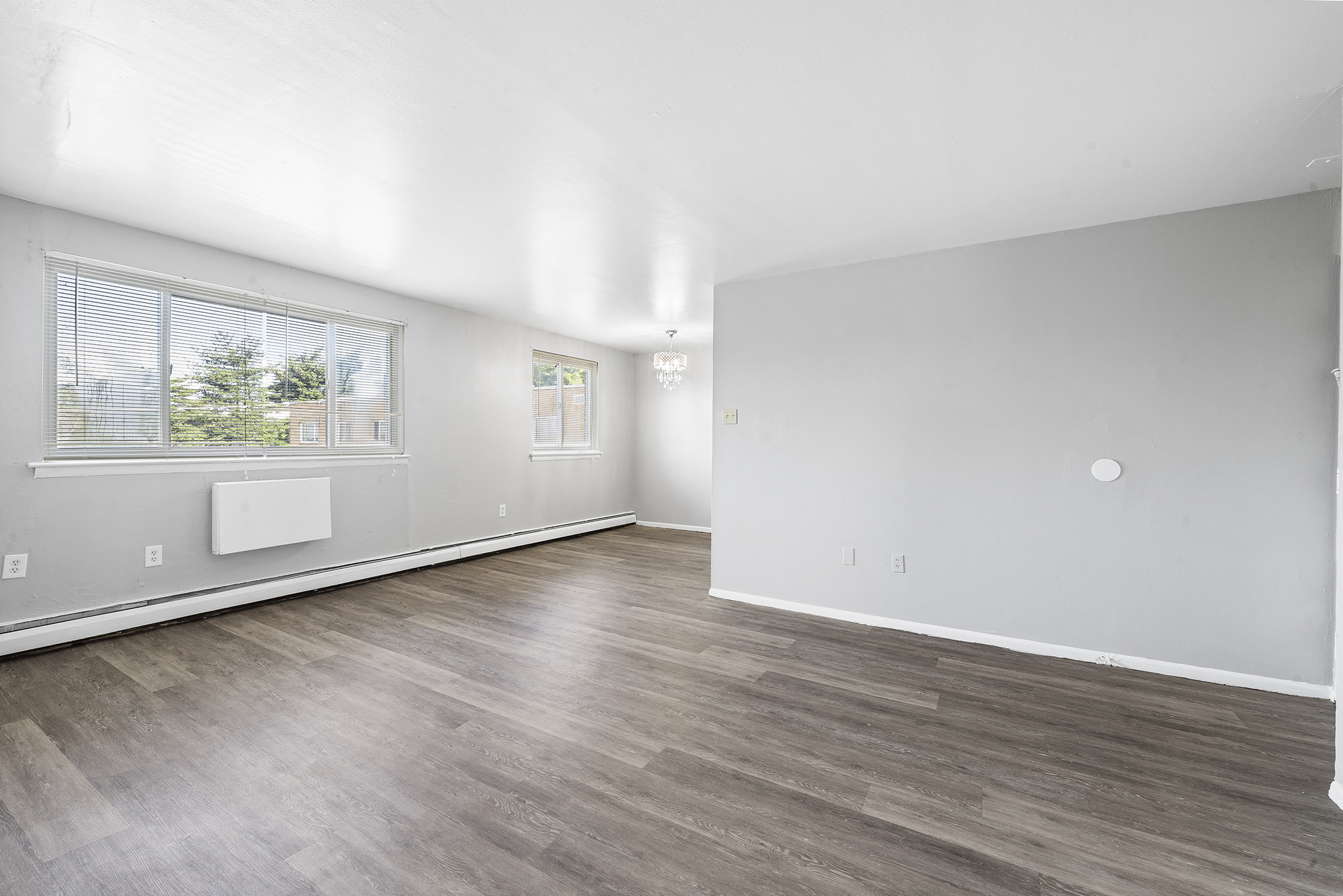 a living room with white walls and wood flooring and a window