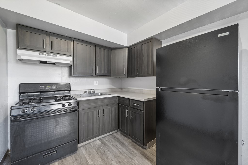 an empty kitchen with black appliances and a refrigerator