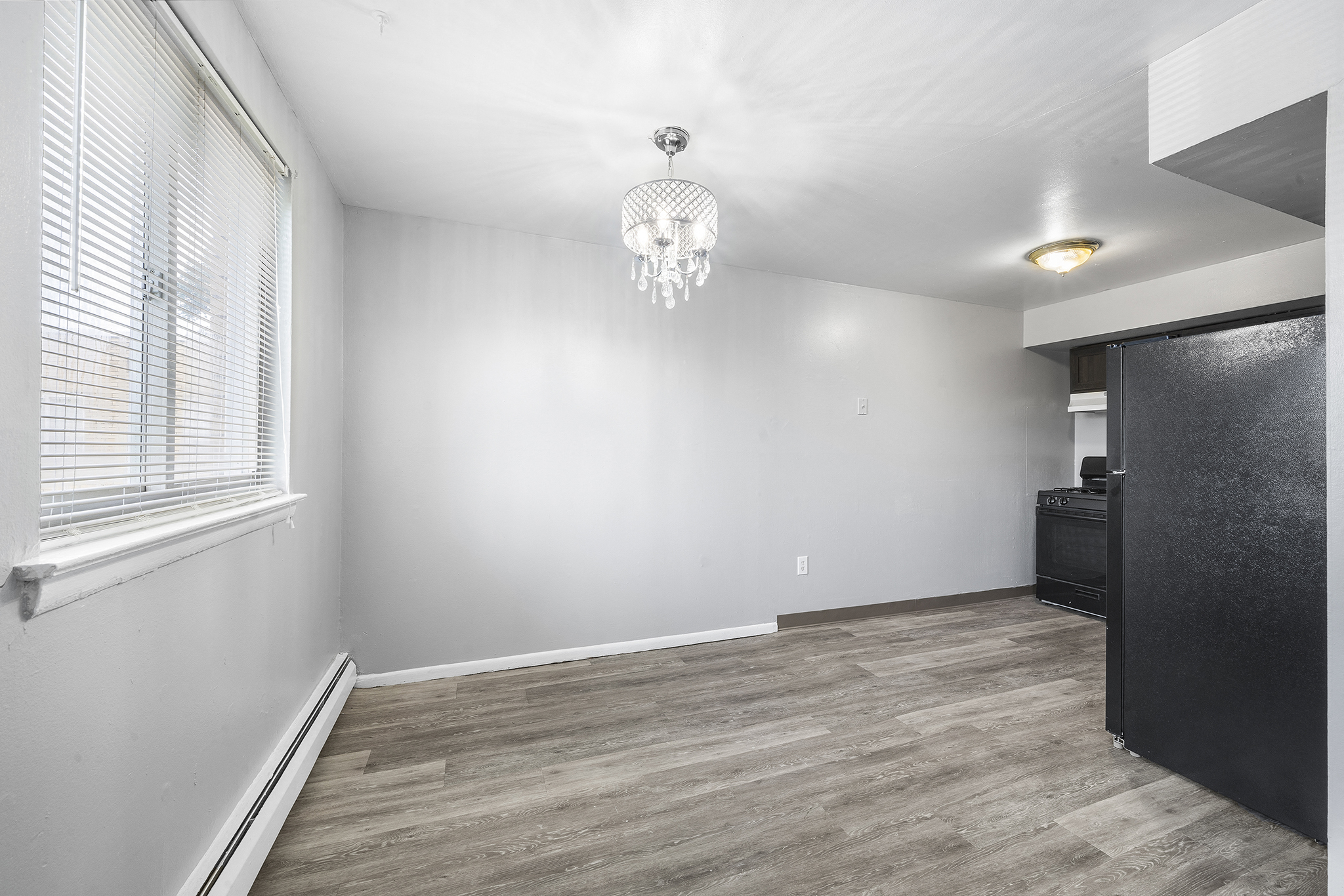 a living room with white walls and wood flooring and a window