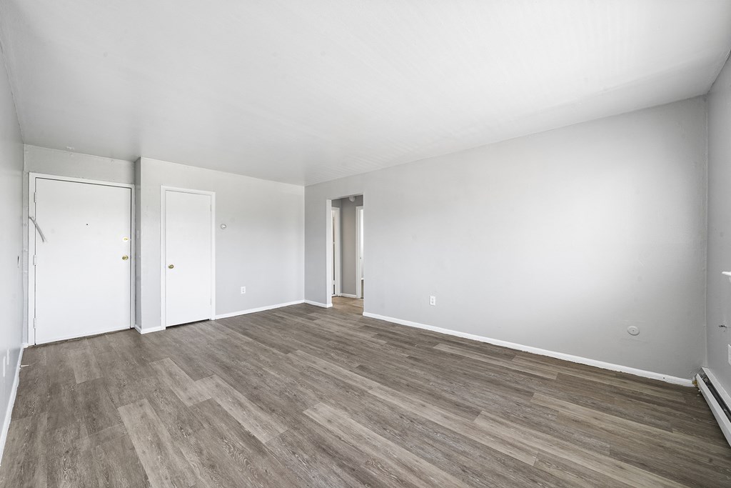 an empty living room with white walls and wood flooring