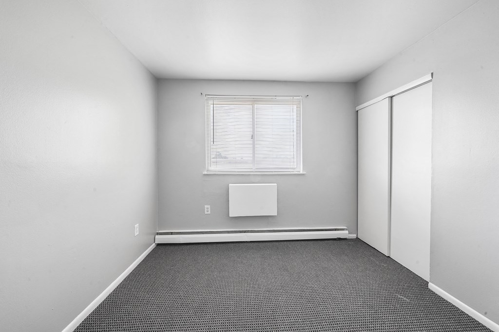 an empty room with a window and white walls