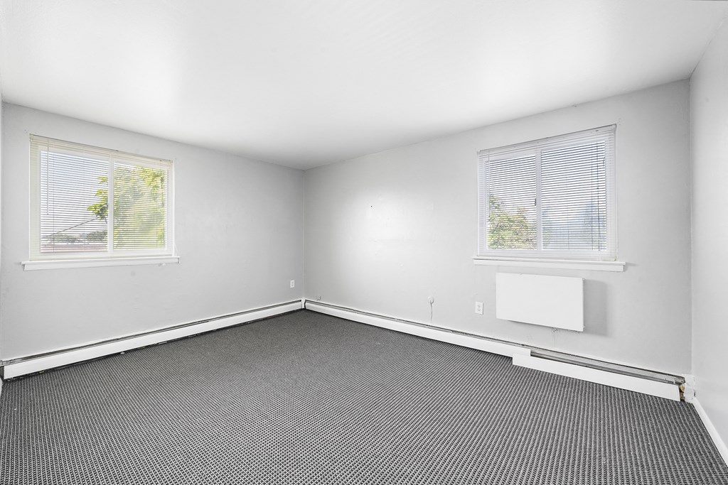 an empty room with a radiator and two windows
