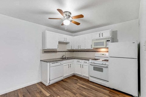 a kitchen with white appliances and a ceiling fan