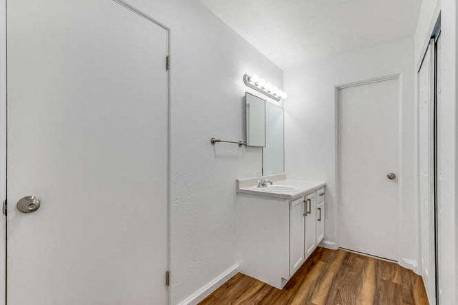 A white bathroom with a mirror and a light above it.