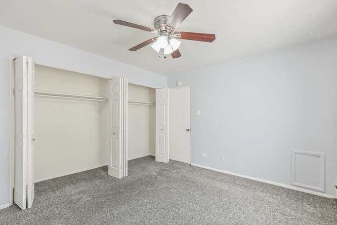 A room with a ceiling fan and carpeted floor.