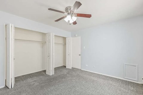 A room with a ceiling fan and carpeted floor.