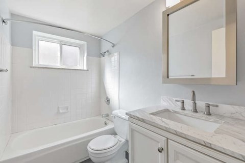 A white bathroom with a tub, toilet and sink.