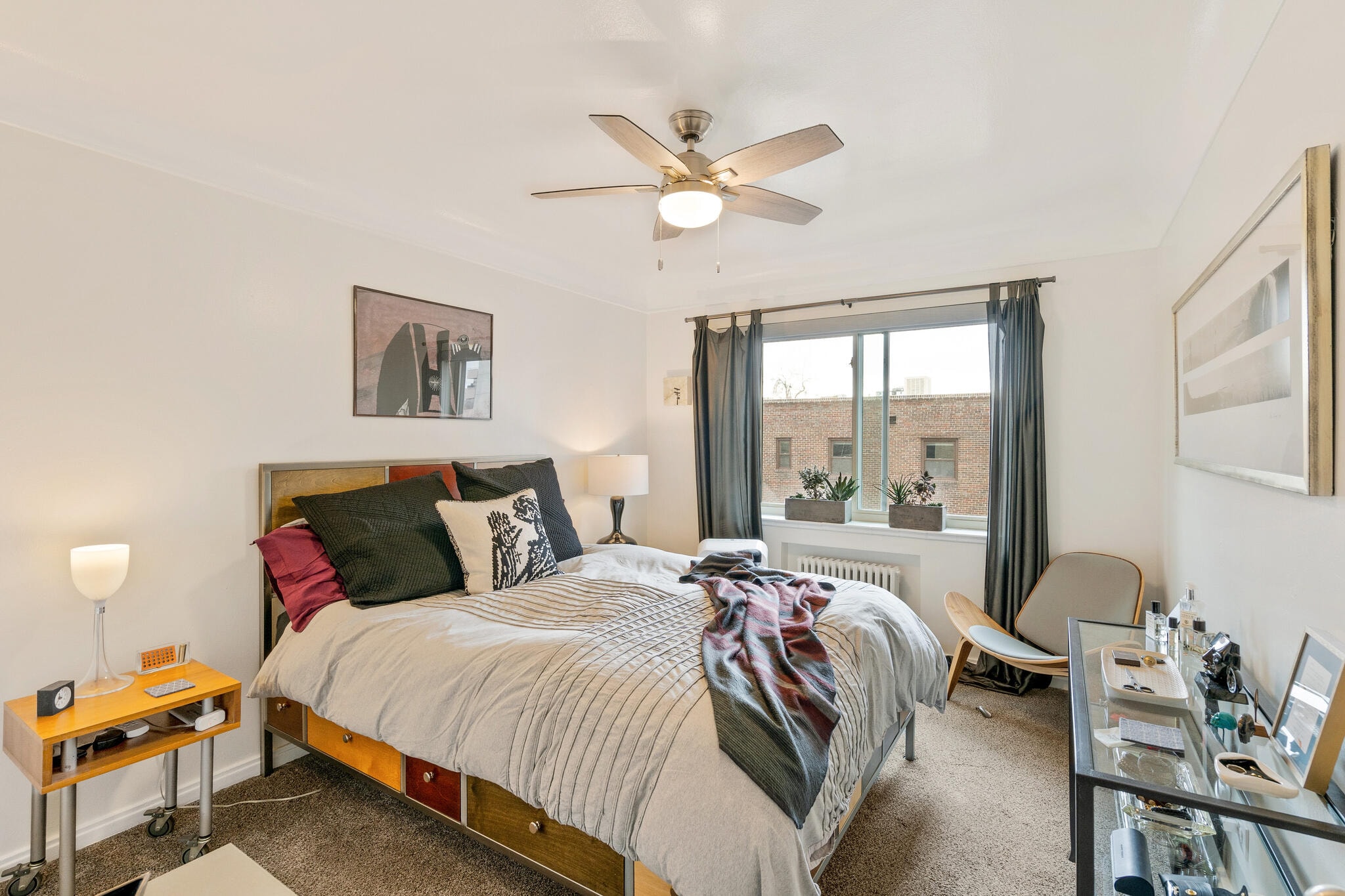 A bedroom with a bed, chair, and a ceiling fan.