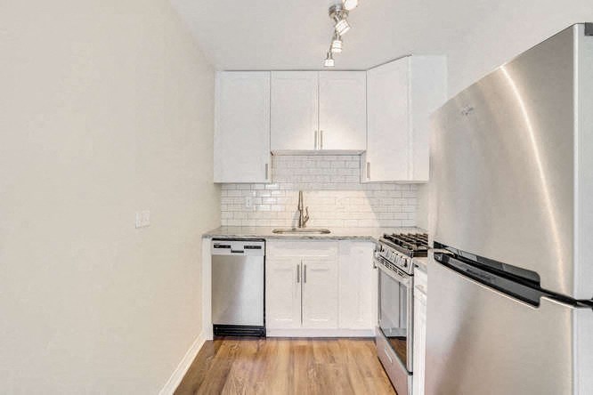 a kitchen with white cabinets and a stainless steel refrigerator