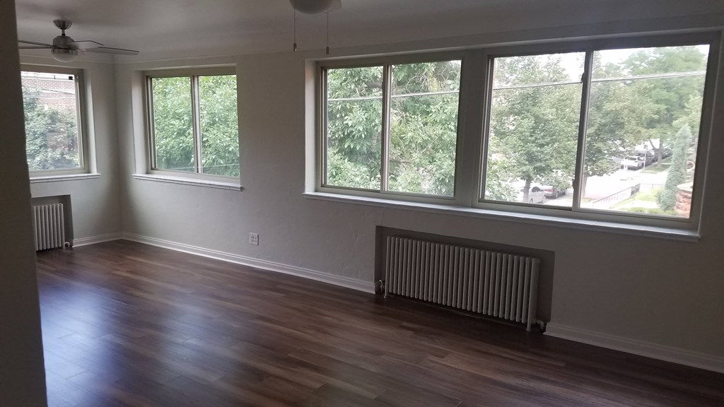 an empty living room with a wood floor and large windows
