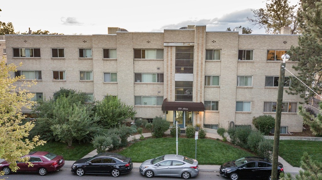 the exterior of an apartment building with cars parked in front