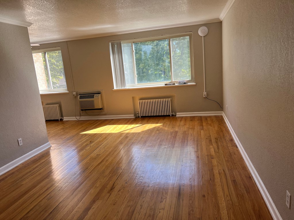 an empty living room with wooden floors and a window