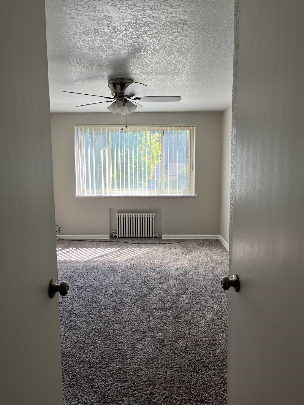 an empty room with a ceiling fan and a window