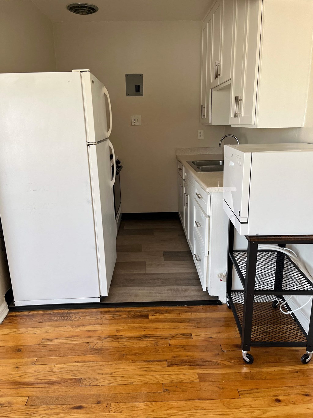 a kitchen with white appliances and a wood floor