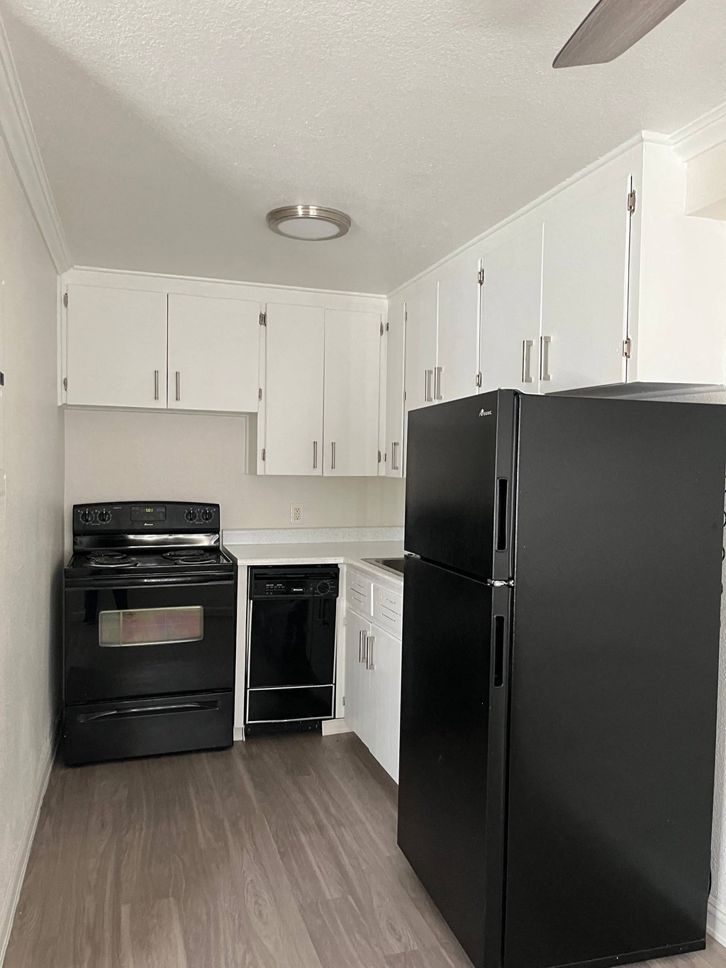 an empty kitchen with black appliances and white cabinets