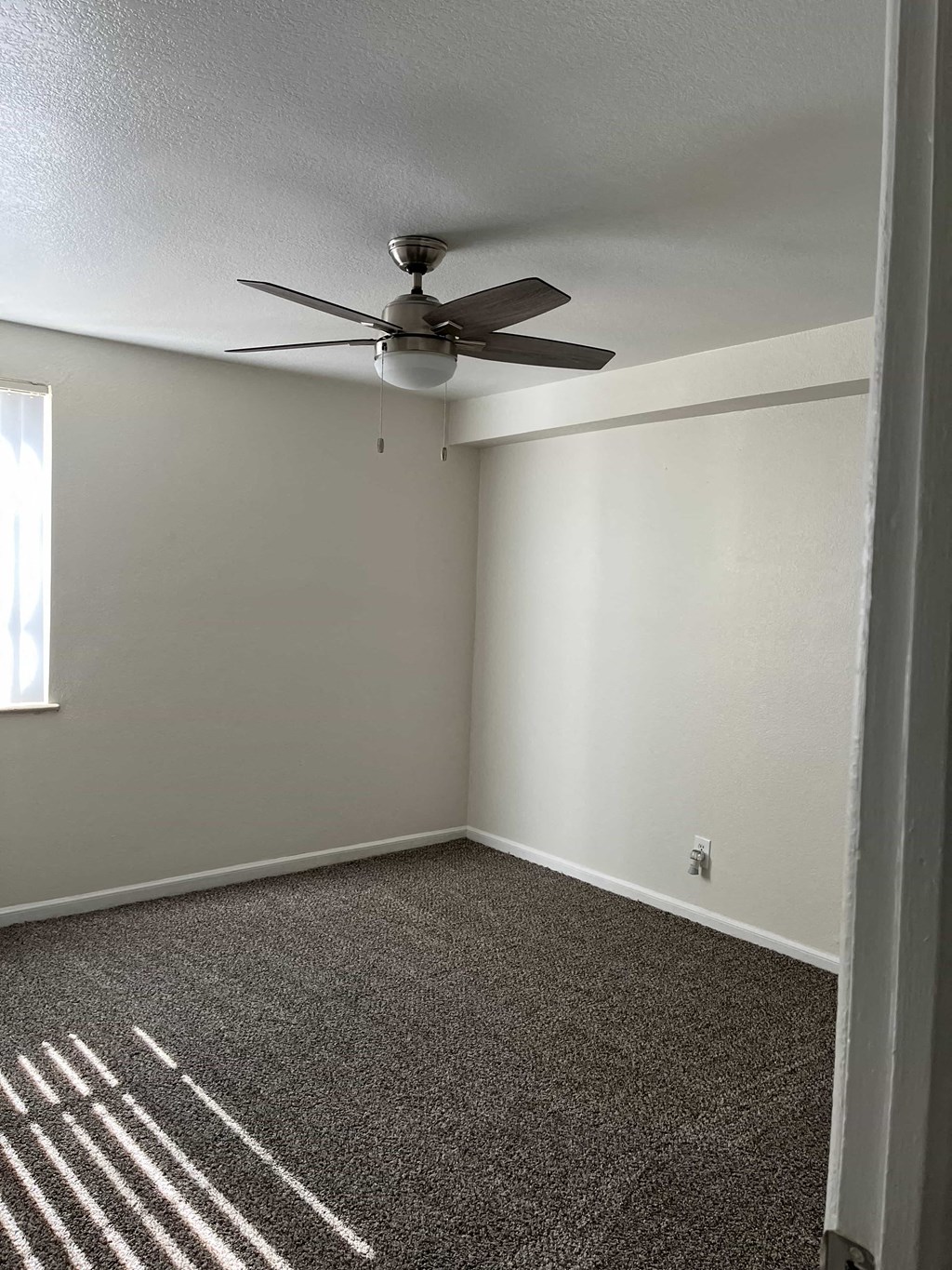an empty room with a ceiling fan and a carpet