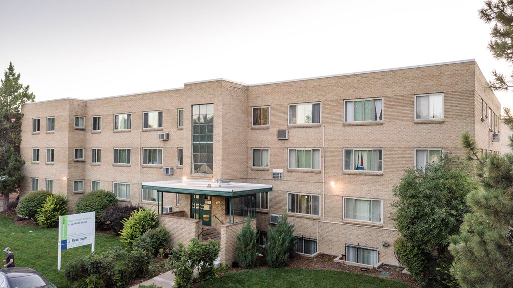 a large brick building with a green yard in front of it
