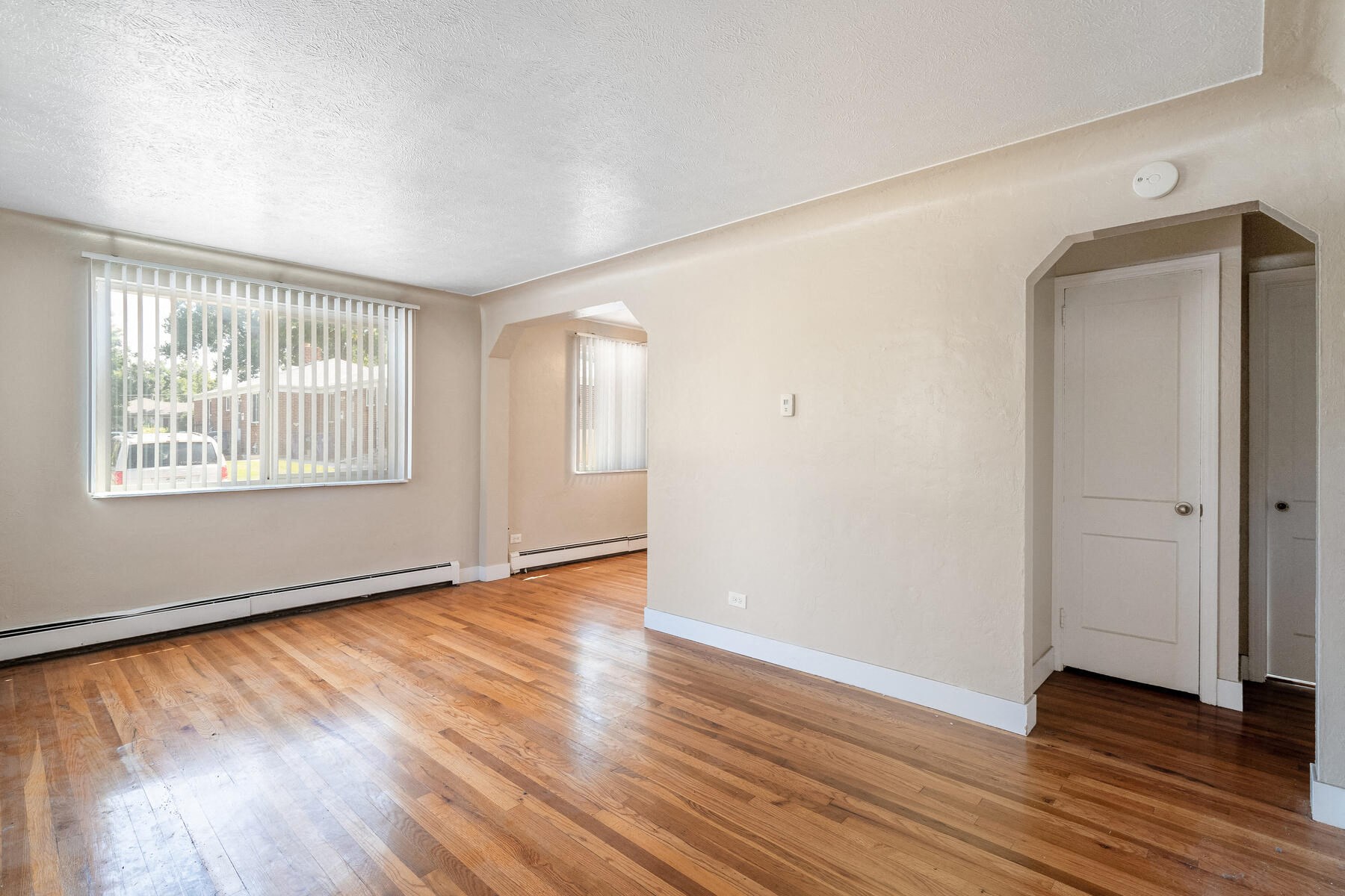 an empty living room with hard wood floors and a window