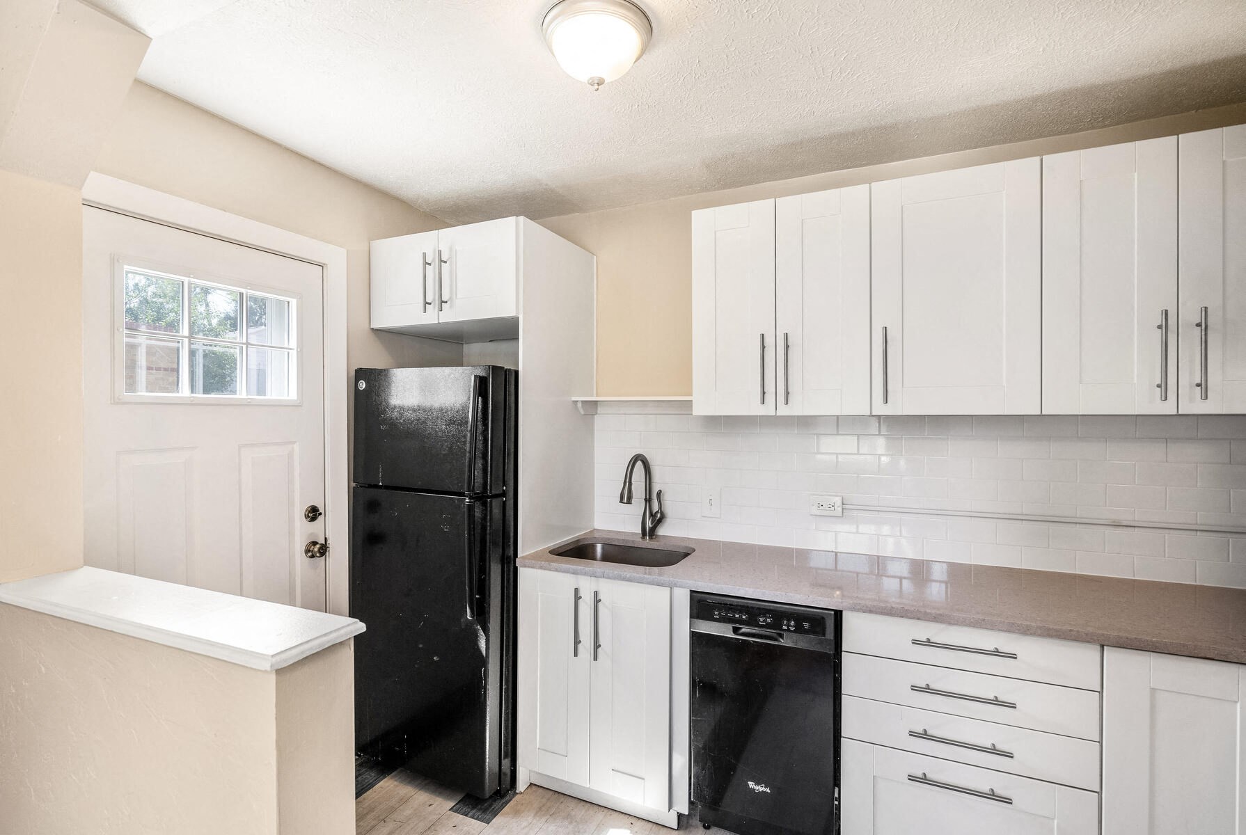 a kitchen with white cabinets and a black refrigerator