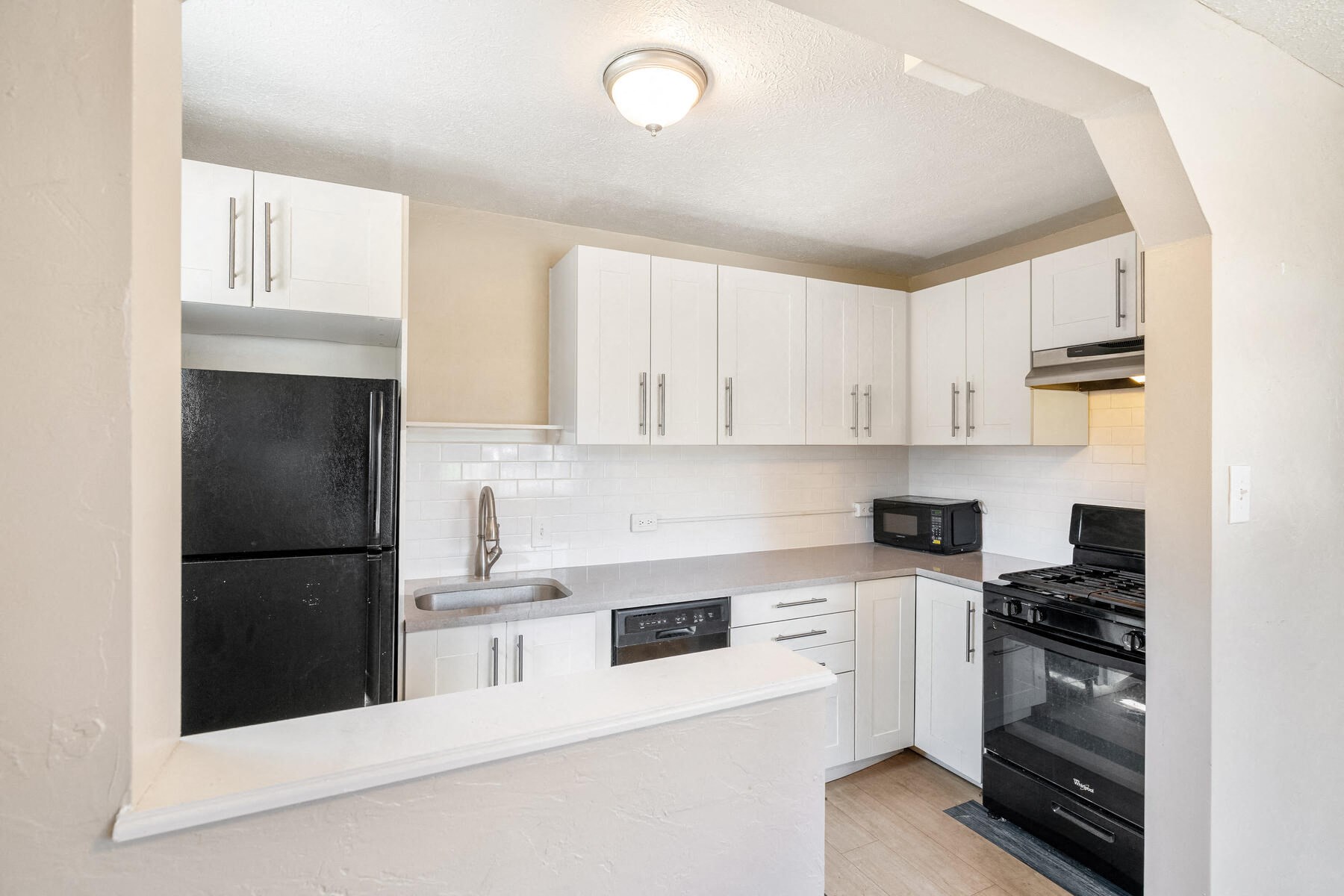 an empty kitchen with white cabinets and black appliances