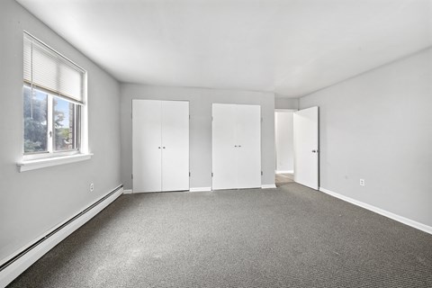 the living room of an apartment with carpet and white walls