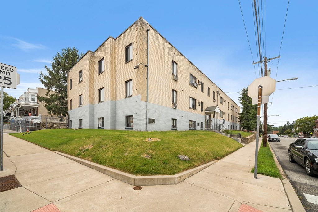 an apartment building on the corner of a sidewalk