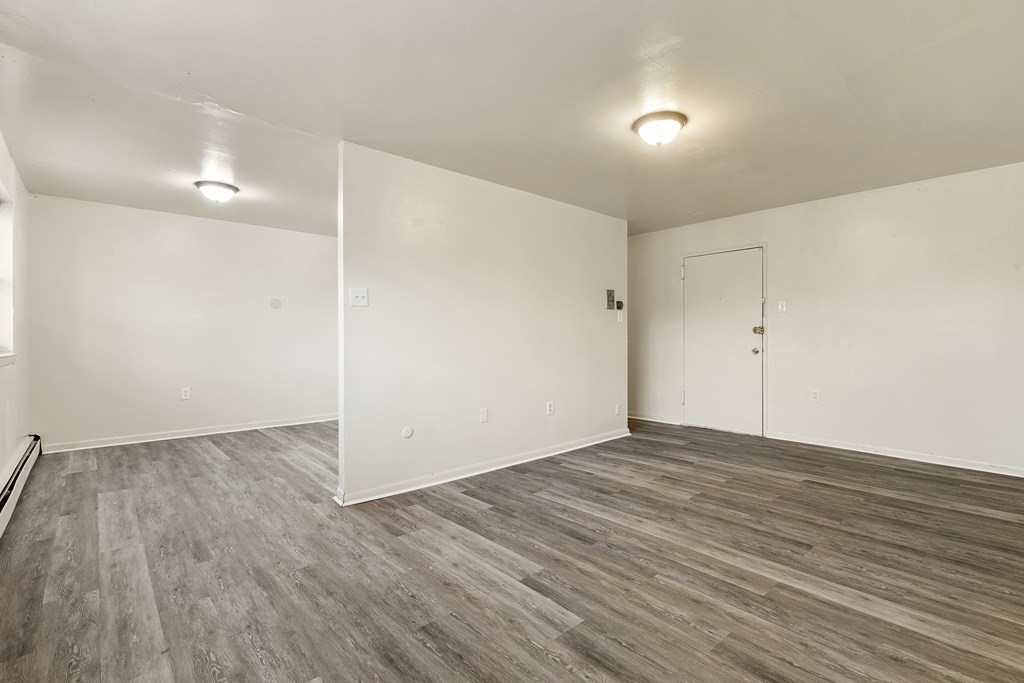 an empty living room with white walls and wood flooring