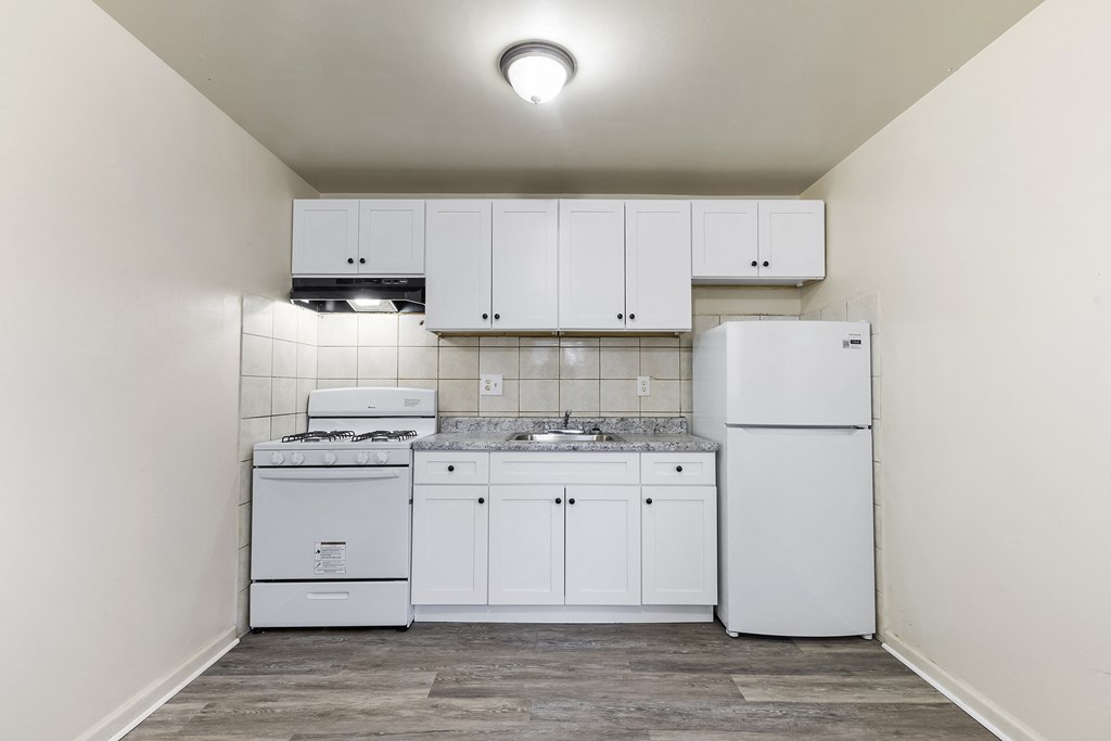 an empty kitchen with white appliances and white cabinets