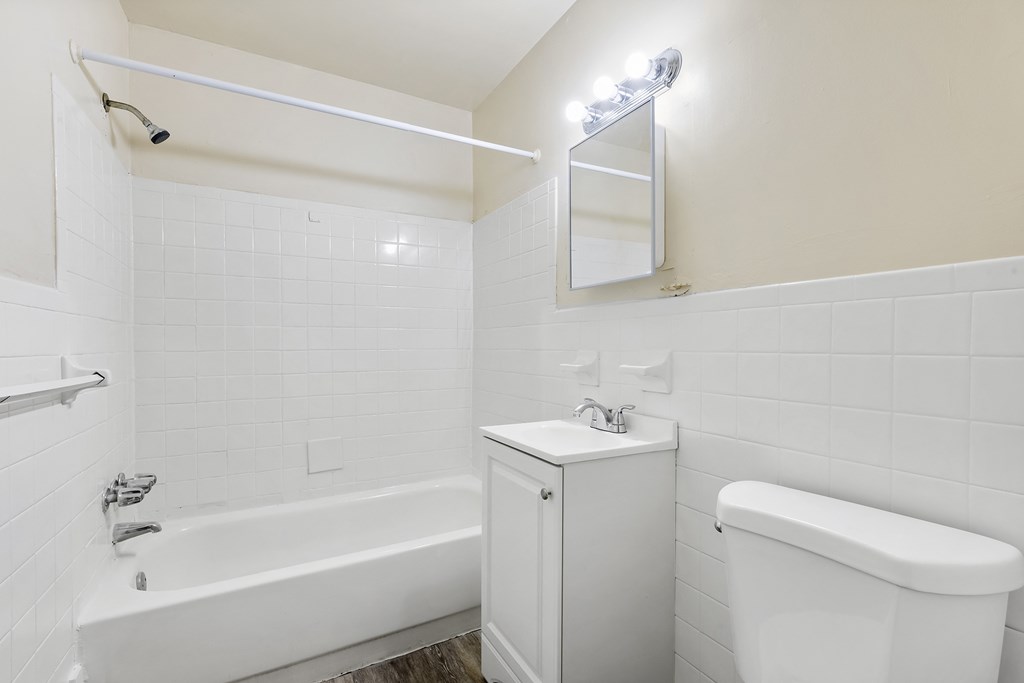 a white bathroom with a tub and a sink and a toilet