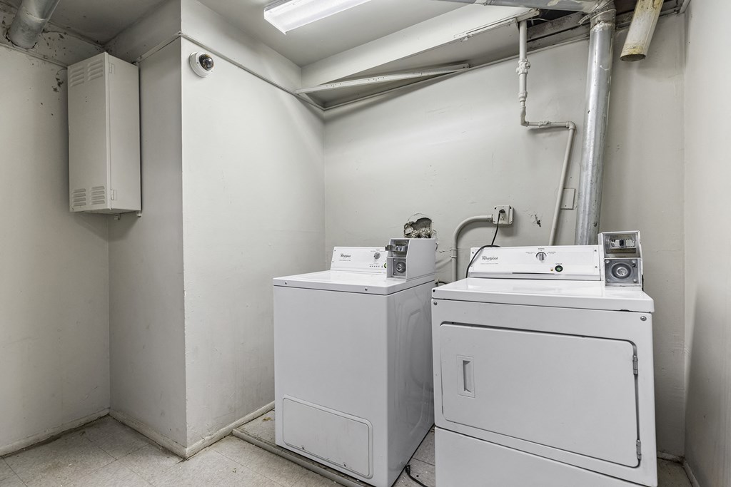 an empty room with two washing machines and a dryer