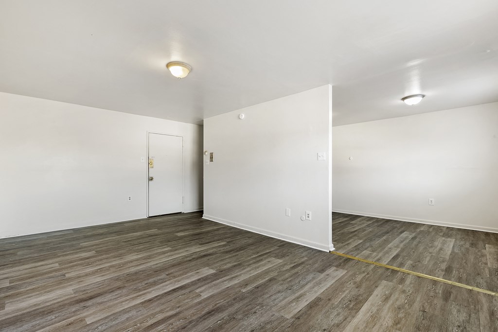a bedroom with white walls and wood flooring and a door