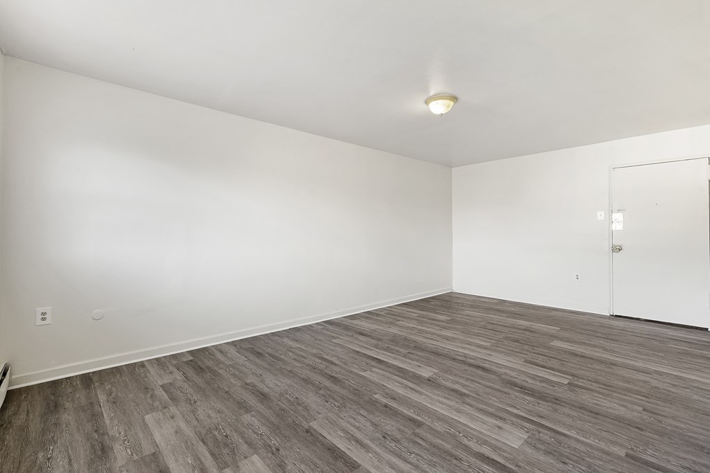 an empty living room with white walls and wood flooring