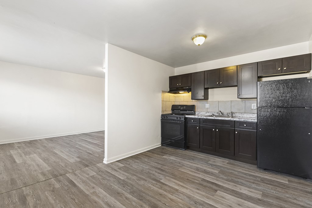 an empty kitchen with black appliances and white walls