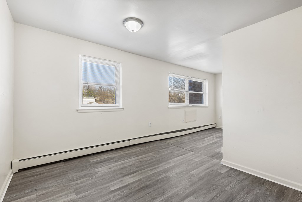 the living room of an apartment with white walls and wood floors