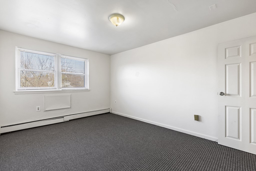 an empty room with white walls and carpet and a white door and window