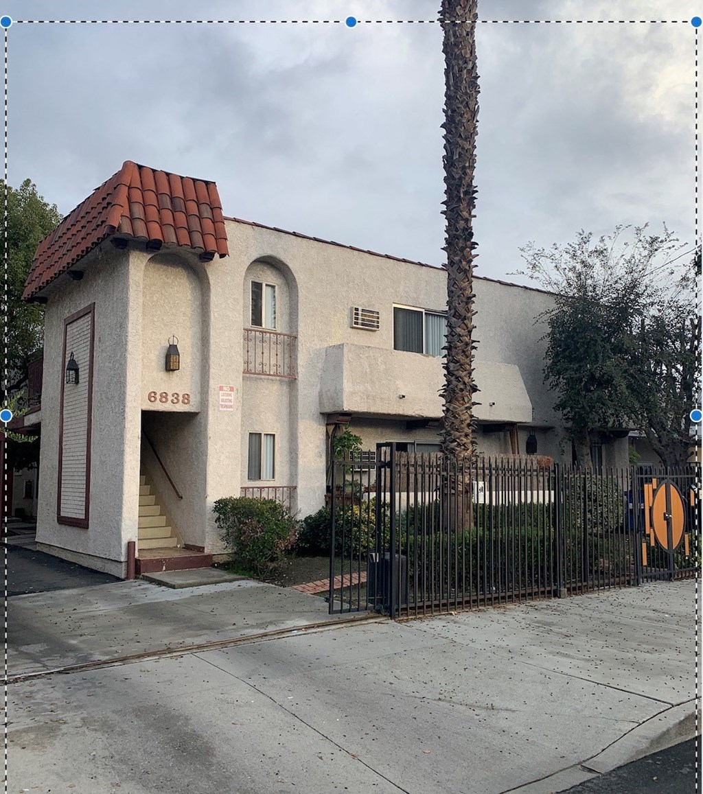 a house with a gate and a palm tree