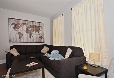 a living room with a brown couch and a painting on the wall