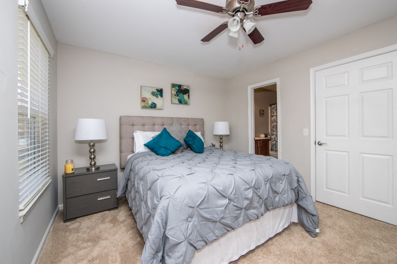 Carpeted bedroom with ceiling fan at Villages at City Center apartments in Newport News VA