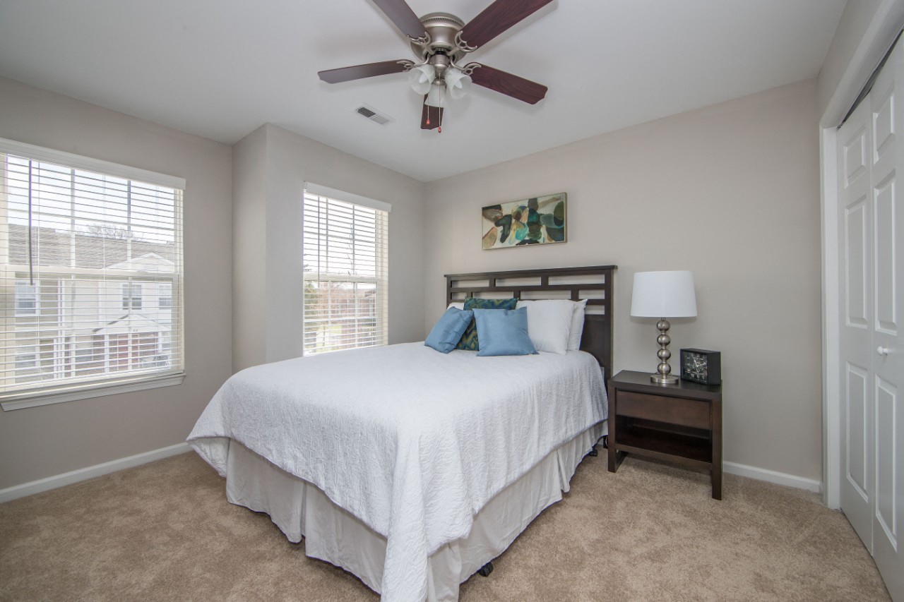 Carpeted bedroom with ceiling fan at Villages at City Center apartments in Newport News VA