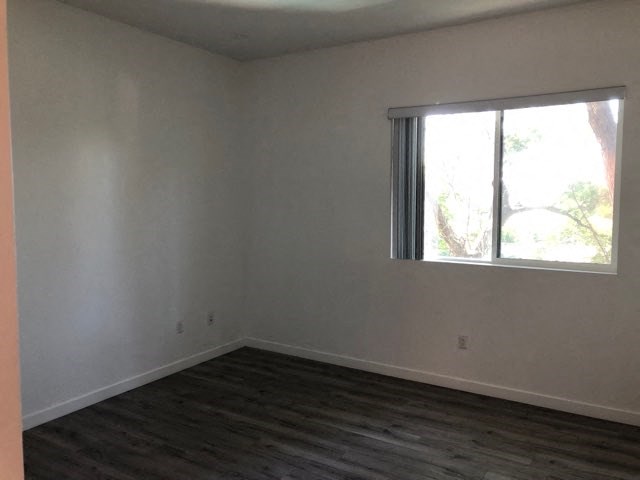 an empty room with a window and wooden floors