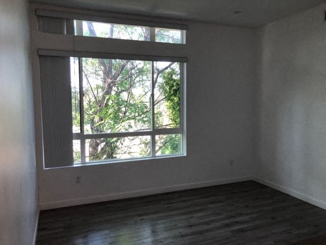 an empty room with a large window and wooden floors