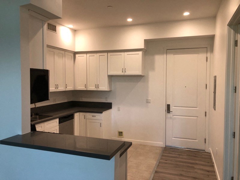 a kitchen with white cabinets and a black counter top