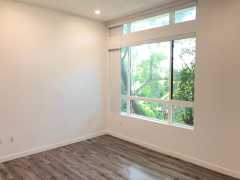a living room with a large window and wooden floors