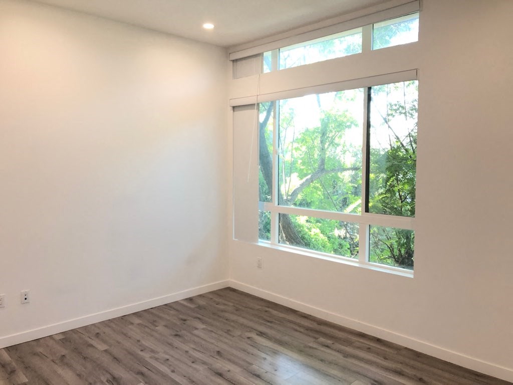 a living room with a large window and wooden floors
