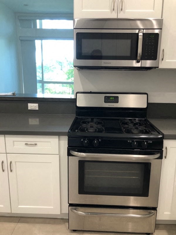 a kitchen with a stove microwave and white cabinets