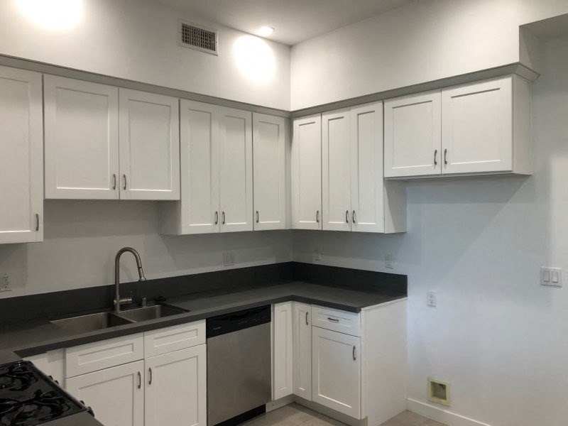 an empty kitchen with white cabinets and a sink