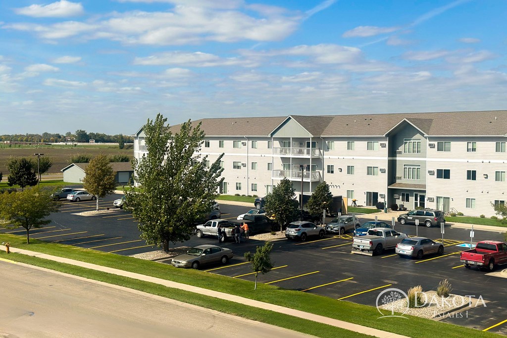 a parking lot with cars in front of an apartment building