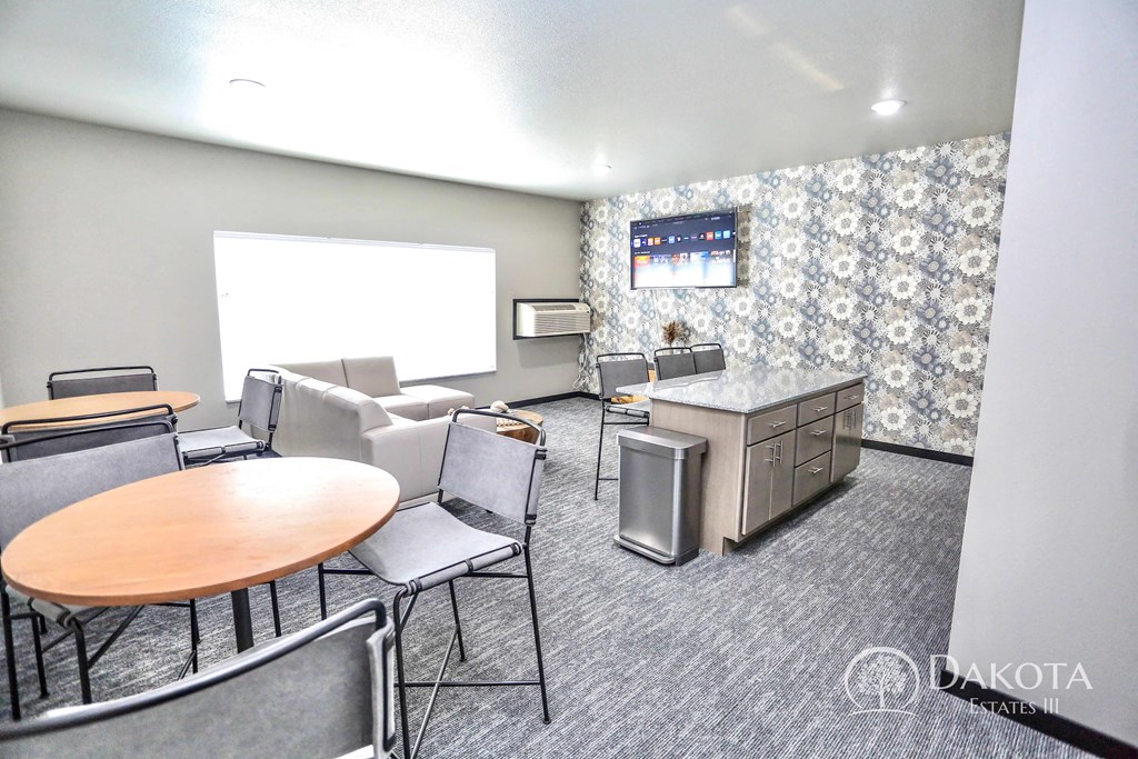 a community room with a table and chairs and a counter with a sink and a