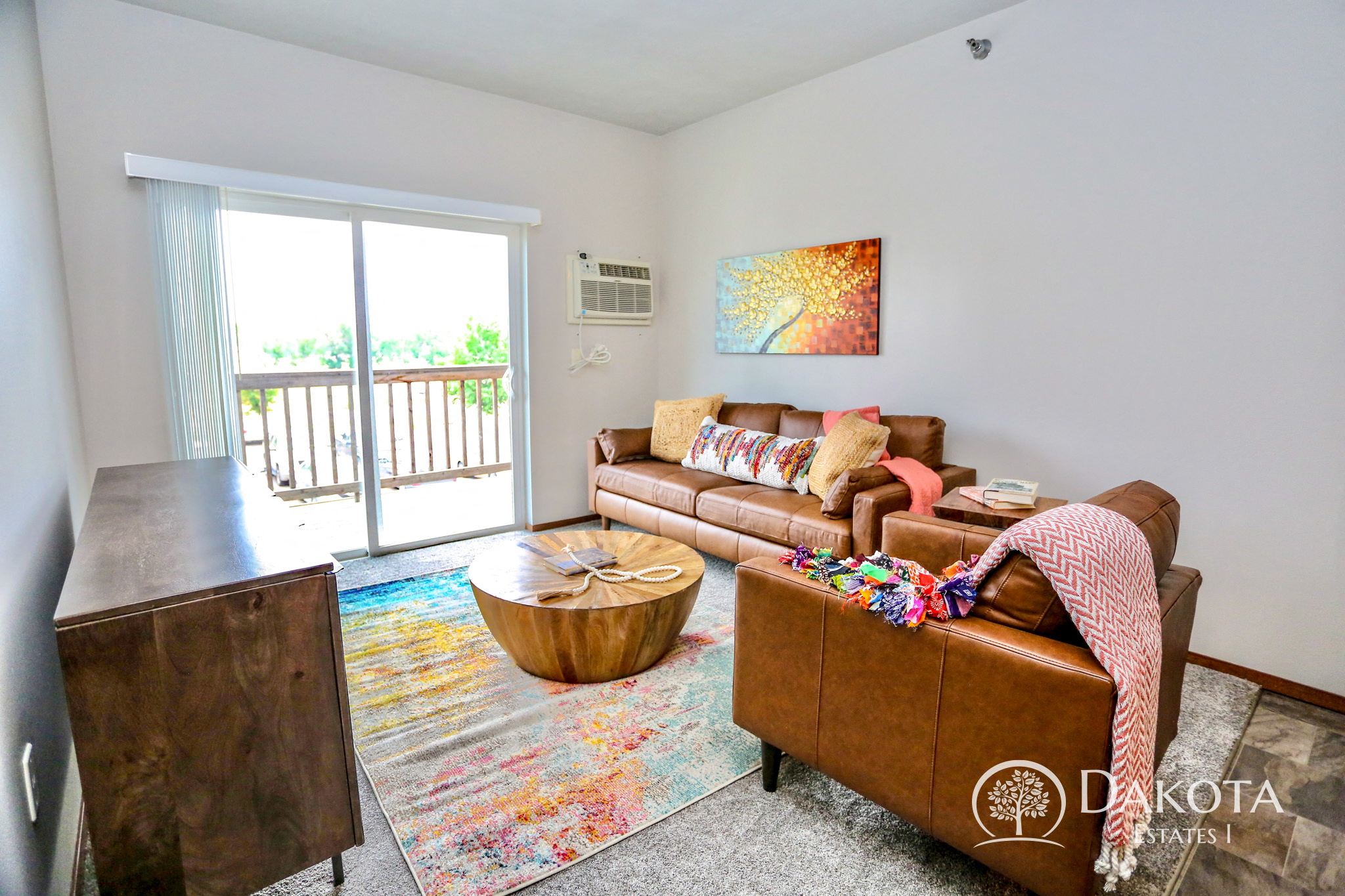A living room with a brown couch and a painting on the wall.