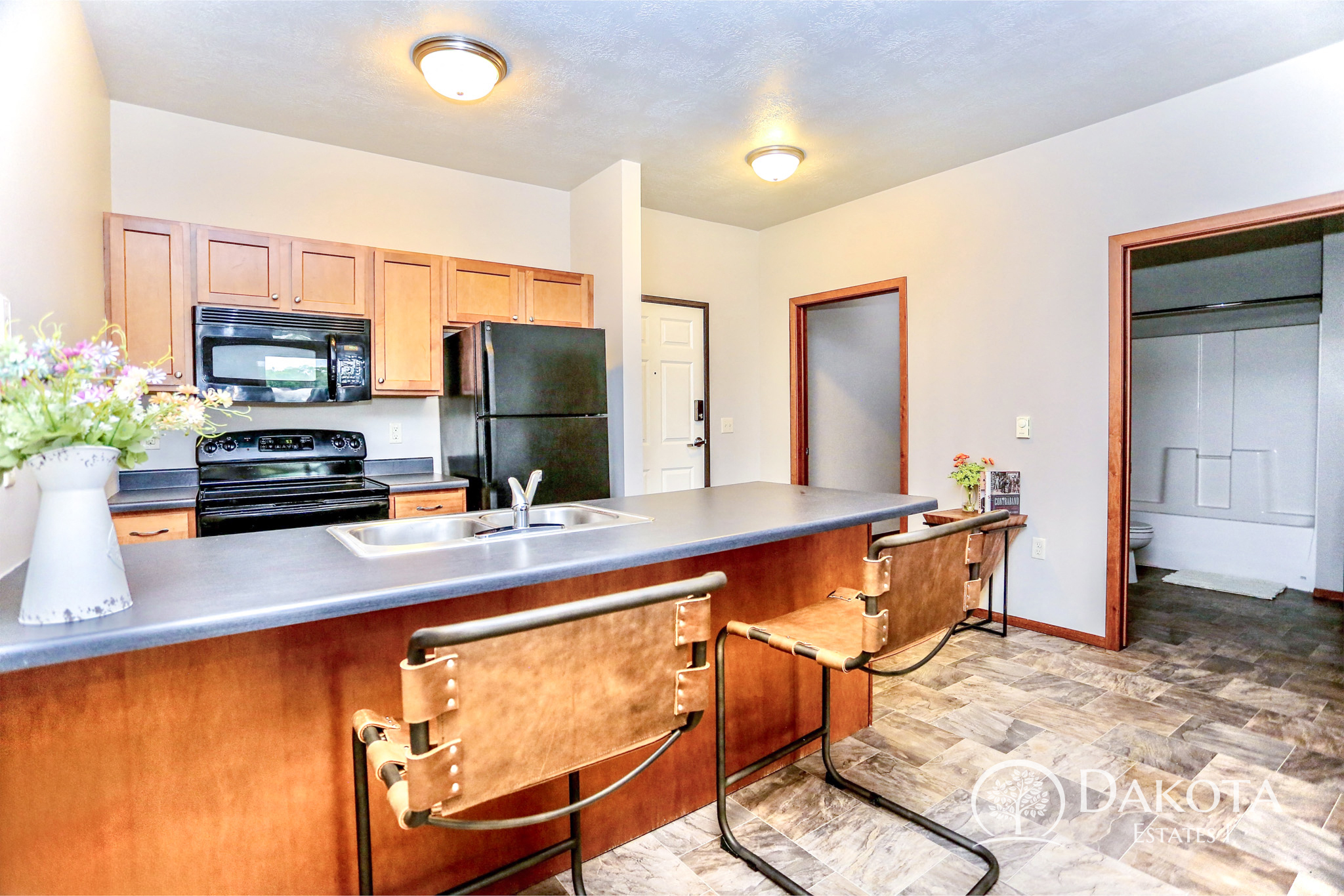 A kitchen with wooden cabinets and a black refrigerator.